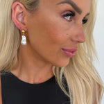 Close-up of a woman wearing gold earrings with a blurred background