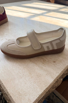 Beige shoe with a strap on a textured surface